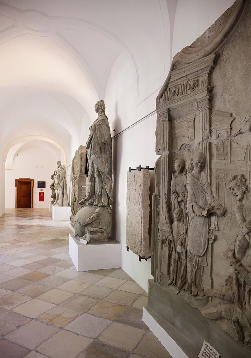Südflügel des Kreuzgangs mit Gedenkplatteen und originalen Sandsteinreliefs der Kirchenfassade